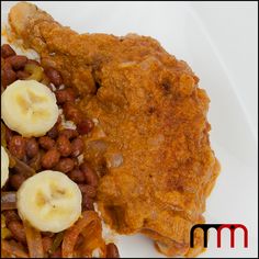 a white plate topped with meat and beans next to banana slices on top of it