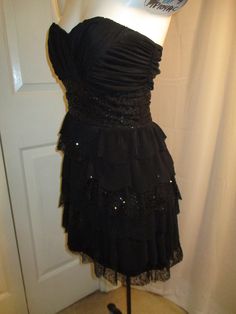 "@ 1980's early 90's. 100% polyester. Hand wash. Back zip. Front and side stays. Built in padded bra. The bodice is nicely draped. Wide sequined band at waist. The fun and flirty ruffled skirt has multi layers, some are perma pleated and some mesh with sequins. It is marked a size 7/8 but would be todays 4. My mannequin is a 2 and it's about a size big. The fabric has some stretch. The skirt measures 16\" from the waist. Laying flat seam to seam it's 16 1/2\" across under the arms, 13\" at the w Strapless Ruffled Dress For Night Out, Strapless Ruffled Corset Evening Dress, Ruched Strapless Dress For Evening Party Season, Ruched Strapless Dress For Party Season, Strapless Ruched Corset Dress For Party, Strapless Evening Corset Dress With Ruffles, Strapless Lined Mini Dress For Party, Lined Strapless Evening Dress, Lined Strapless Dress For Party