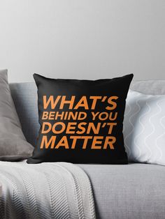 a black and orange pillow with the words, what's behind you doesn't matter