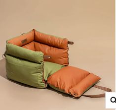 an orange and green sleeping bag sitting on top of a brown floor next to a tan wall