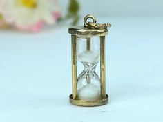 This unique vintage sand clock charm in 14K yellow gold is an actual working hourglass filed with real natural sand! Dating from the 1960's, this clever conversation piece is a great reminder of the precious nature of life and measures 22.0mm high and 10.0mm, weight 2.2 gram, hallmark 14K, JMF Hourglass Pendant, Sand Clock, 1960s Vintage, Conversation Piece, Unique Vintage, 1960s, Clock, Charms, Yellow Gold