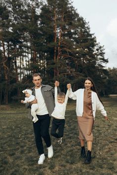 a man, woman and child are walking in the grass with their hands up as if they were celebrating