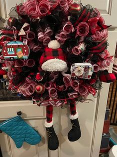 a red and black christmas wreath hanging on the front door with santa's stocking around it