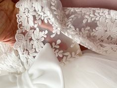 a woman's hand is touching the lace on her wedding dress