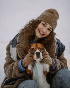 a woman sitting on the ground holding a dog in her lap and smiling at the camera