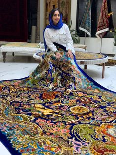 a woman sitting on top of a colorful rug