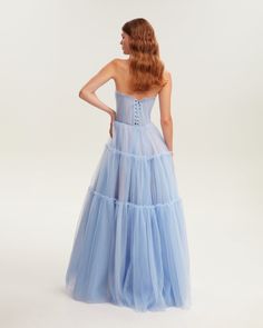 Dreamy tulle dress in light blue color with a light ruffled tulle maxi skirt. This dress has a heart-shaped boned semi-transparent bodice with built-in cups and a corset back, which makes the silhouette fitted and elegant. The A-line maxi skirt is made from multiple layers of delicate tulle that emphasize the hourglass silhouette. The waistline is adorned with a silver belt with Milla’s signature.This dress comes with straps, adding an elegant touch. Details: Material: Tulle Fabric composition: Voluminous Floor-length Tulle Dress, Voluminous Tulle Floor-length Dress, Blue Gown With Tulle Skirt And Fitted Bodice, Floor-length Voluminous Tulle Dress, Blue Tulle Dress With Boned Bodice, Prom Season Maxi Tulle Dress, Maxi Length Tulle Skirt Prom Dress, Blue Evening Dress With Voluminous Skirt, Maxi Length Organza Gown With Tulle Skirt