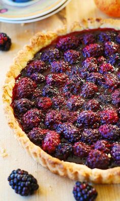 the pie is ready to be eaten with berries on top and blackberries around it