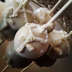 some cake pops with white frosting and beads are on a stick in a basket