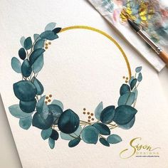 a watercolor painting of a wreath with green leaves and gold trim on white paper