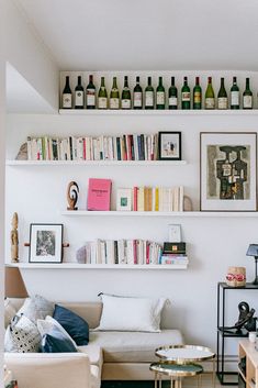 a living room filled with furniture and lots of bottles on the wall above it's bookshelves