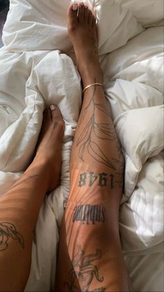 a person laying in bed with tattoos on their legs