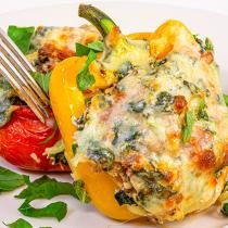 an eggplant stuffed bell peppers with spinach and tomatoes on a white plate