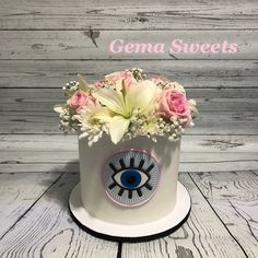 a white hat with pink flowers and an evil eye on the front, says gena sweets