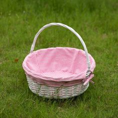 a pink and white basket sitting in the grass