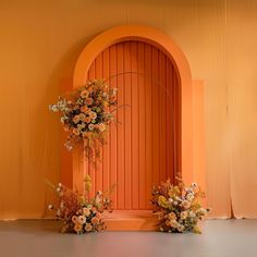 two vases filled with flowers sitting on top of a table next to an orange wall