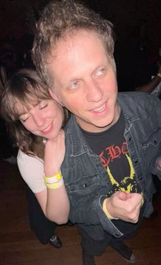 a man and woman are posing for a photo in front of the camera with their arms around each other