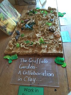 a cake made to look like a garden is displayed on a table with a sign that says, the grifffato garden a collaboration in clay