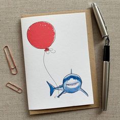 a card with an image of a shark holding a red balloon on top of it