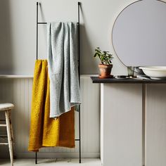 a towel hanging on a rack next to a table with a potted plant in it