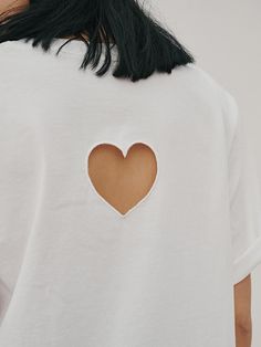 a woman wearing a white t - shirt with a heart cut in the back