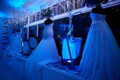 wedding dresses are displayed on display in front of a window with blue lights behind them