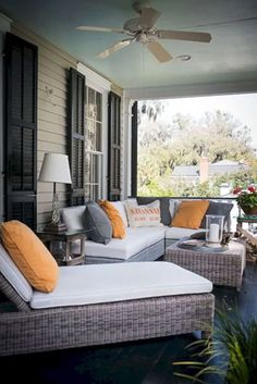 an outdoor living area with couches and pillows on the front porch, surrounded by greenery