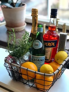 a basket filled with liquor and lemons on top of a table next to a potted plant