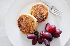 two pancakes and grapes on a plate with a fork