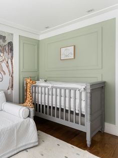 a baby's room with a giraffe painting on the wall