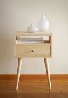 two white vases sitting on top of a wooden table next to a book shelf