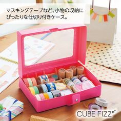 a pink box filled with lots of different types of washi tapes on top of a wooden table