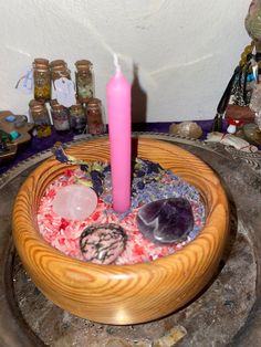 a wooden bowl with rocks and a pink candle