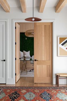 an open door leading to a living room with wood floors and white walls, along with a rug on the floor