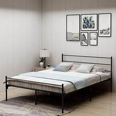 a bed sitting on top of a wooden floor next to a wall with pictures above it