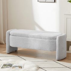 a gray bench sitting on top of a wooden floor next to a white rug in a living room