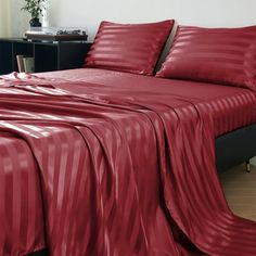 a bed with red sheets and pillows in a room