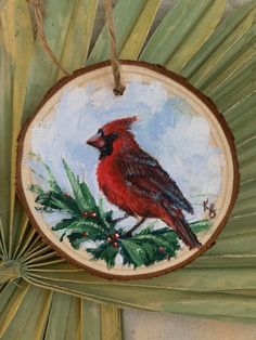 a red bird sitting on top of a green plant next to a palm frond