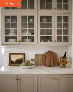 a kitchen with white cabinets and marble counter tops, gold accents on the bottom cabinet