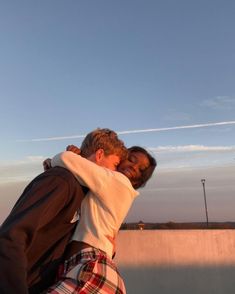 a man and woman hugging each other in front of a skateboard ramp at sunset