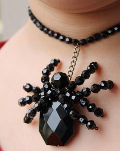 a woman wearing a black beaded necklace with a spider charm on it's neck