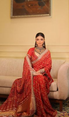 a woman sitting on top of a couch wearing a red sari