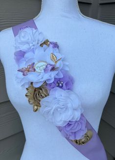 a white mannequin with purple and gold flowers on it's neck,