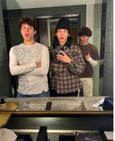 three young men standing in front of a mirror