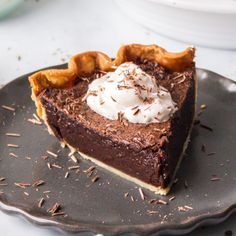 a piece of chocolate pie with whipped cream on top is sitting on a black plate