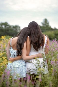 two young women hugging in a field of wildflowers