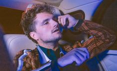 a man sitting in the back seat of a car while talking on a cell phone