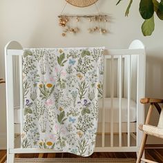 a white crib with a floral blanket hanging from it's side