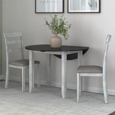 a dining table with two chairs and a vase on the table in front of it