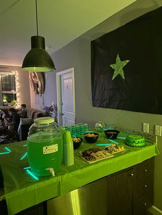 a green table topped with lots of food next to a black and white painting on the wall